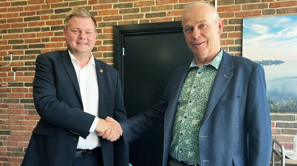 Borgmester i Guldborgsund Kommune, Simon Hansen (tv.), og næstformand i  VKST, John Nielsen (th.) giver hånd på den partnerskabsaftale, der forpligter parterne til et tæt samarbejde om reduktion af CO2-udledningen. Foto: Guldborgsund Kommune