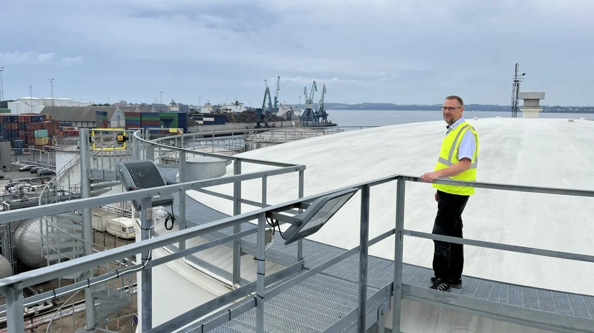 Lars Hindbo er kravlet højt til vejrs på én af de 10.000-liters tanke, som gør DanGødning i stand til nu at tage større skibe ind ved kajen foran skrotpladsen i baggrunden. Foto: Kasper Stougård