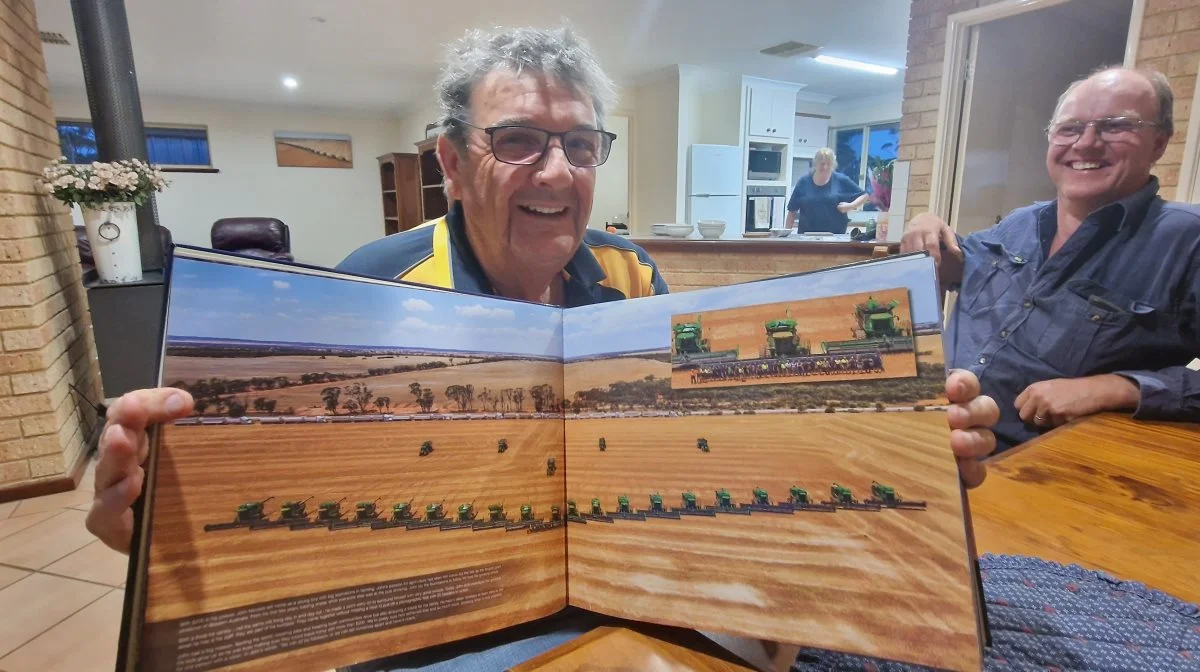 John Nicoletti viser et billede fra 2019 af sine daværende 20 John Deere-mejetærskere, 5 kornvogne og langs vejen 20 trucks til at køre kornet væk, ved aftensmaden hos Brian Østergaard (th).