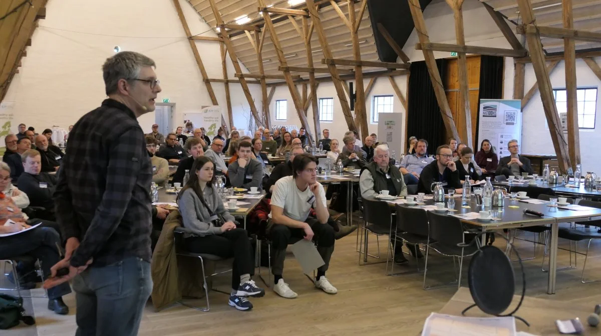 En del af en forskers arbejdsmetode består i at informere og modtage kritik og spørgsmål fra tværfaglige miljøer blandt forskerkolleger, rådgivere og praktikere. Her står adjunkt og forsker ved Institut for Agroøkologi,  AU Viborg , Martin Thorsøe, skoleret overfor kolleger og rådgivere ved en konference på Nørre Vosborg. Han har netop præsenteret et oplæg om kulstoflagring som forretningsmodel og ramlet ind i spørgsmålet om den høje pris for at dokumentere kulstoflagringen i jorden.
