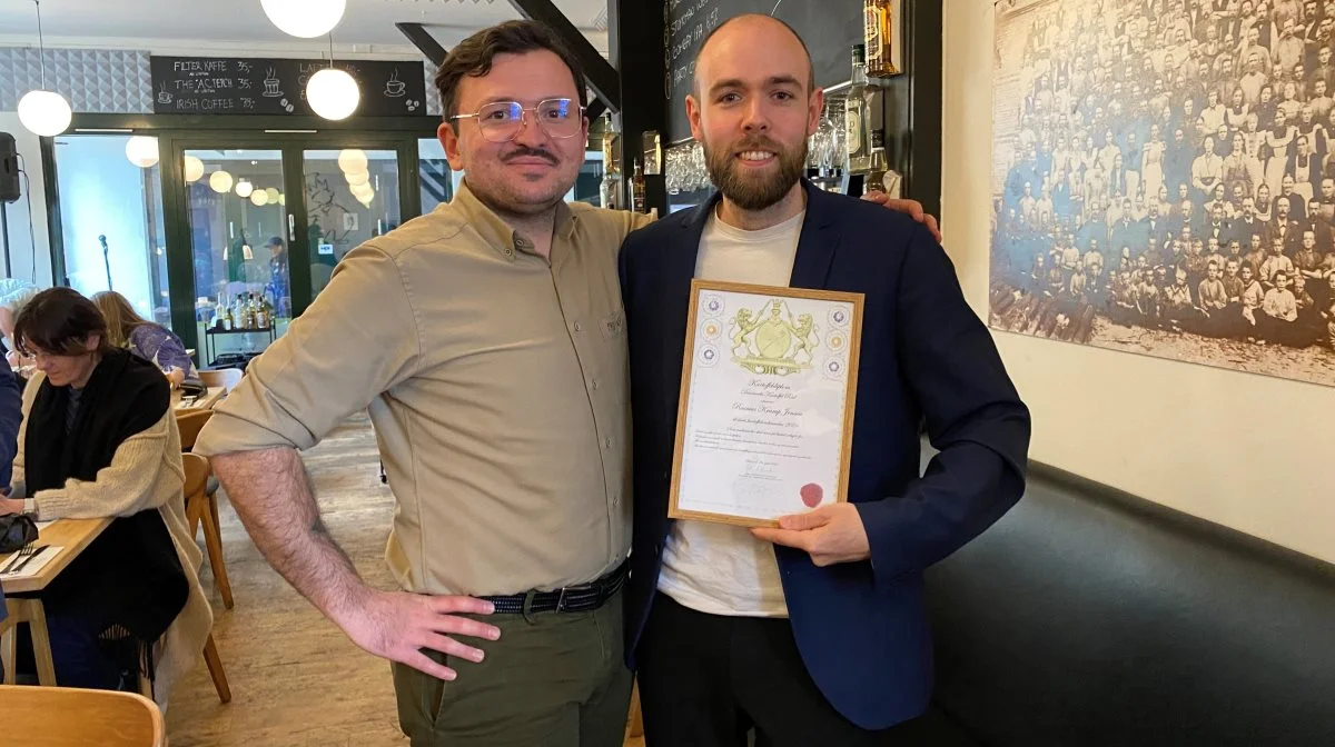 Kok Umut Sakarya (tv.) overdrog titlen som årets Kartoffelambassadør til kogebogsforfatter Rasmus Krarup Jensen ved et officielt arrangement på restaurant Kong Volmer i Odense. Pressefoto