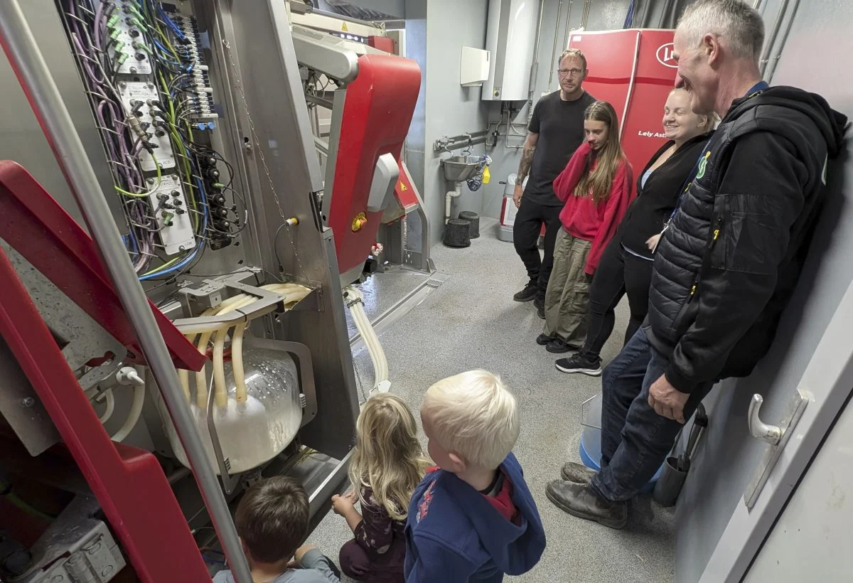 Palle Bjerggaard Hansen forklarer om malkerobotten til Mie Gammelgaard, 11-årige Leyla Ibrahim, og svogeren Søren Stokholm, imens børnene Martim, Alija og Adrian betragter mælken. Fotos: Erik Hansen