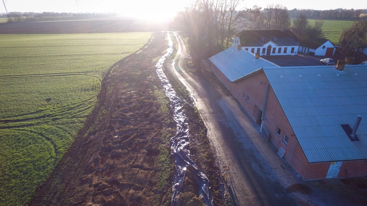Det nordjyske landmandspar fik hjælp af en lokal entreprenør til at grave en fem meter dyb voldgrav rundt om bedriften, som de siden fyldte med plastik for at afværge den løbske strøm. Foto: Torben Farum