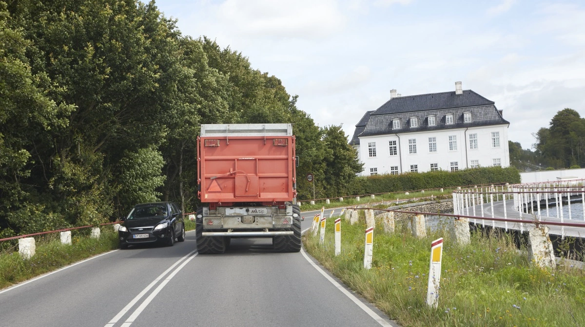 Ad de smalle sydfynske veje fragtes kornet hjem til Hvidkilde Gods. Til højre den nylagte cykelsti på bropiller i Hvidkilde Sø.
