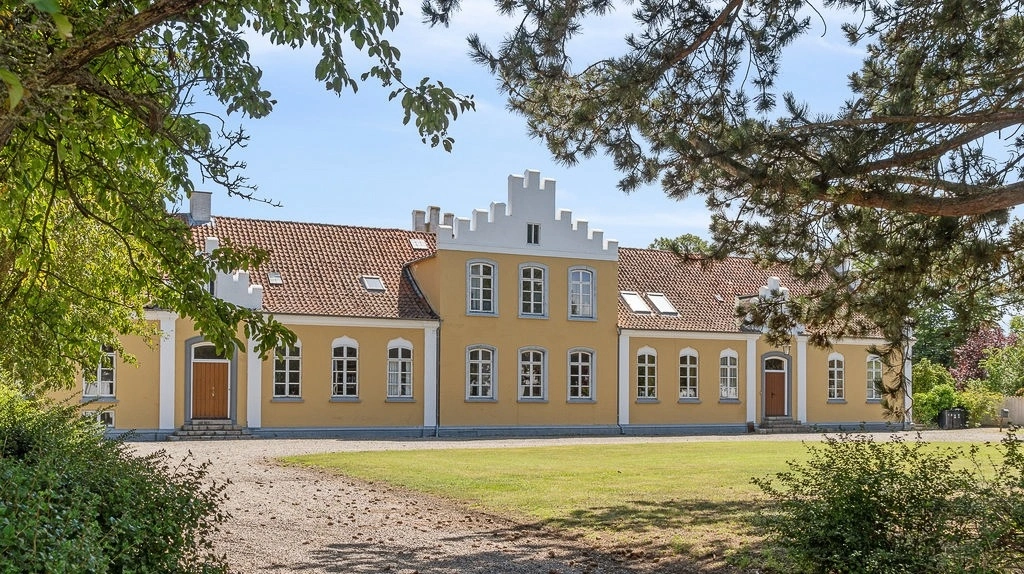 Hovedbygningen på Nakskov Ladegaard er opført i 1848 og rummer 500 kvadratmeter bolig i klassisk herregårdsstil med kamtakkede gavle og frontspidser.