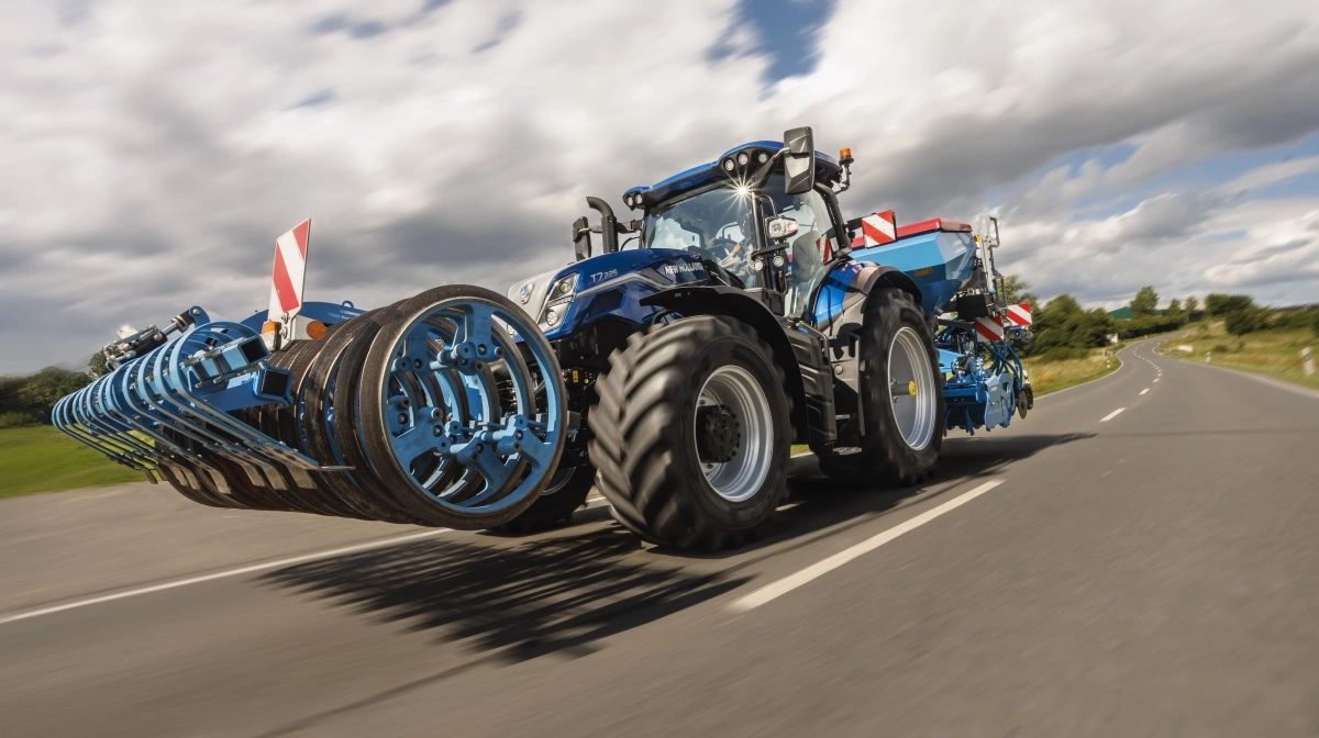 New Holland T7.225 Standard Wheelbase i Dynamic Blue-lakering under transportkørsel med liftophængt såsæt. Den nye affjedrede foraksel med dobbelte akkumulatorer og roll control-funktion forbedrer stabilitet og komfort ved høj hastighed, mens venderadiusen er reduceret med 2,4 meter fra 14,3 til 11,4 meter, der skyldes nyt forakselophæng og lavere motorhjelm. Traktoren er udstyret med 24x24 Dynamic Command-transmission. Pressefotos