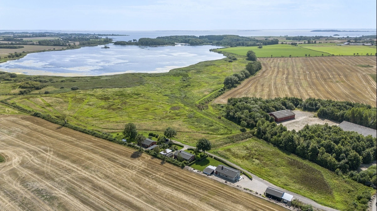 Ejendommene i landzone nær Nakkebølle Gods er placeret tæt på marker og engarealer med udsigt til søen – et område med både lejeindtægter og mulighed for udbygning.
