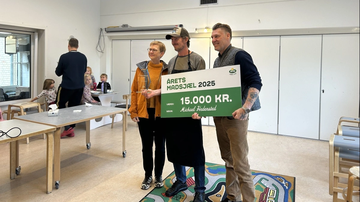 Midt i børnenes frokost blev Michael Hedensted, kost- og ernæringsansvarlig på Søskrænten Daginstitution i Stavtrup, overrasket på sin arbejdsplads af Timm Vladimir og Sanne Vinther fra Arla Fonden, der dukkede op med gavecheck, diplom og kåring som Årets Madsjæl 2025. Foto: Arla Foods