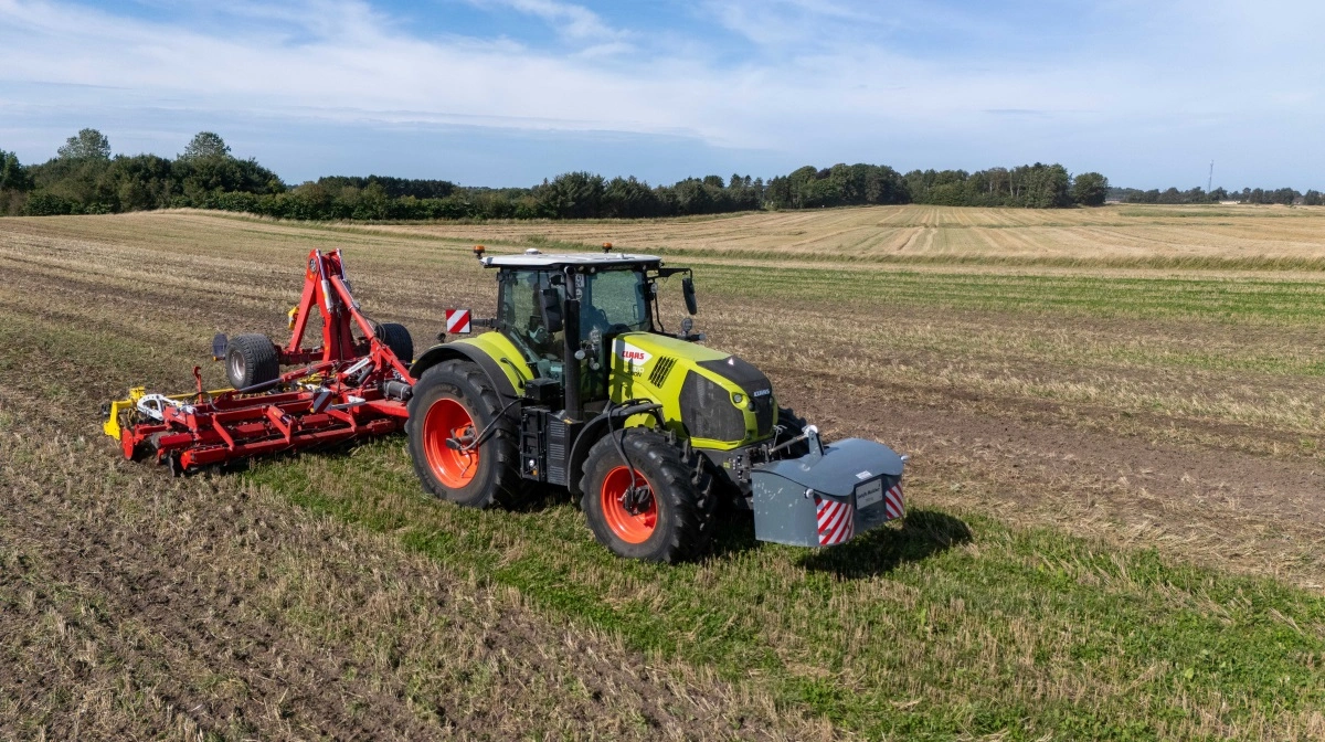 Claas Axion 870 med dæktryksregulering og frontvægt på arbejde i marken.