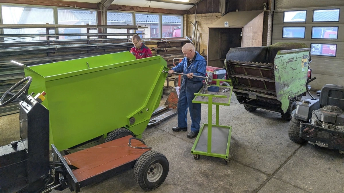 En af de mange aktiviteter på værkstedet er opbygning og renovering af KL Trucks. Her er far og søn, Egon og Allan Jensen, ved at færdigmontere en fodertruck, mens en anden venter på reparation.