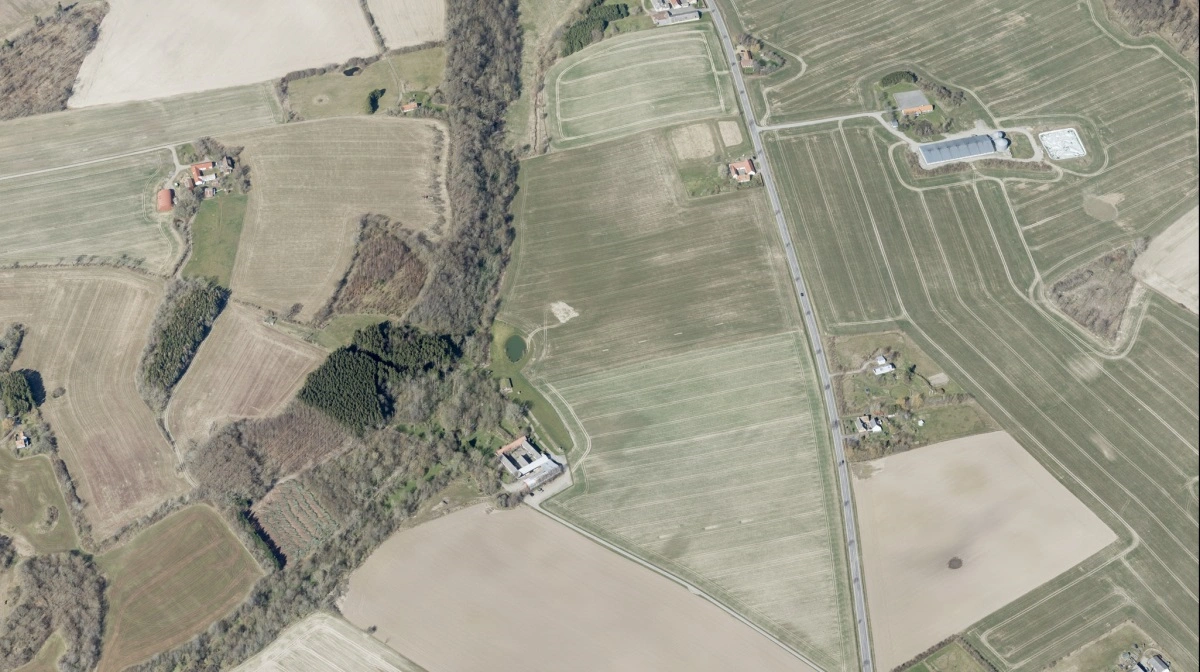 Lokalområdet omkring Pæregård nær Gudhjem på Bornholm er præget af landbrug og marker, som billedet her viser. Det er Pæregård i midten af billedet. Foto: Skråfoto/Styrelsen for Dataforsyning og Infrastruktur