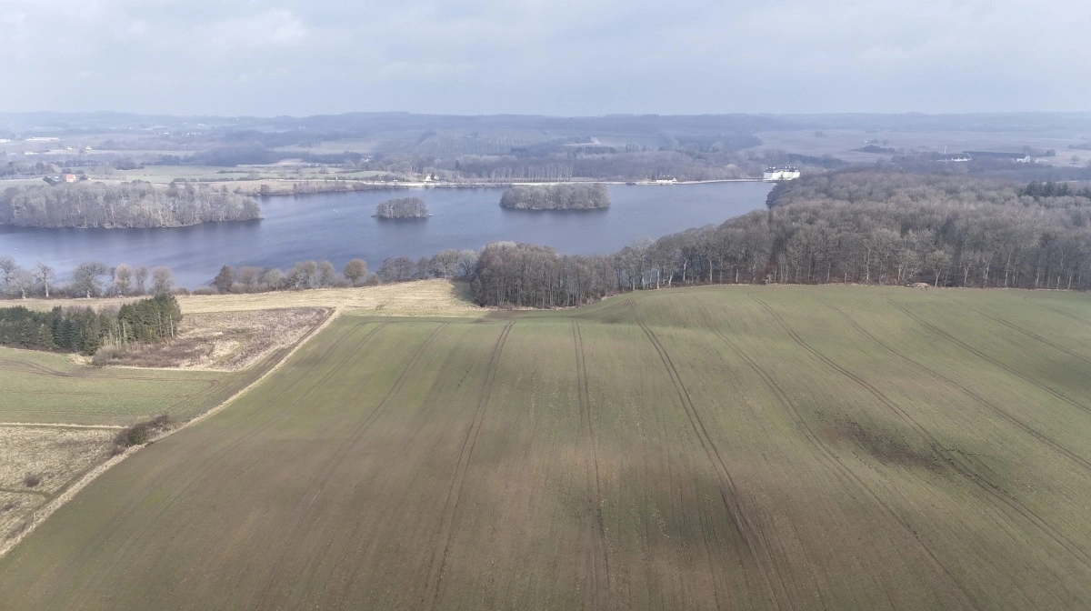 Med beliggenheden ved Det Sydfynske Øhav og det kommende signaturprojekt »Den Sydfynske Højderyg« samt større grundvandsforekomster er Hvidkilde Gods udfordret af politiske tiltag. Billedet viser forårsgrønne marker ved Hvidkilde Sø med de sydfynske bakker i horisonten.