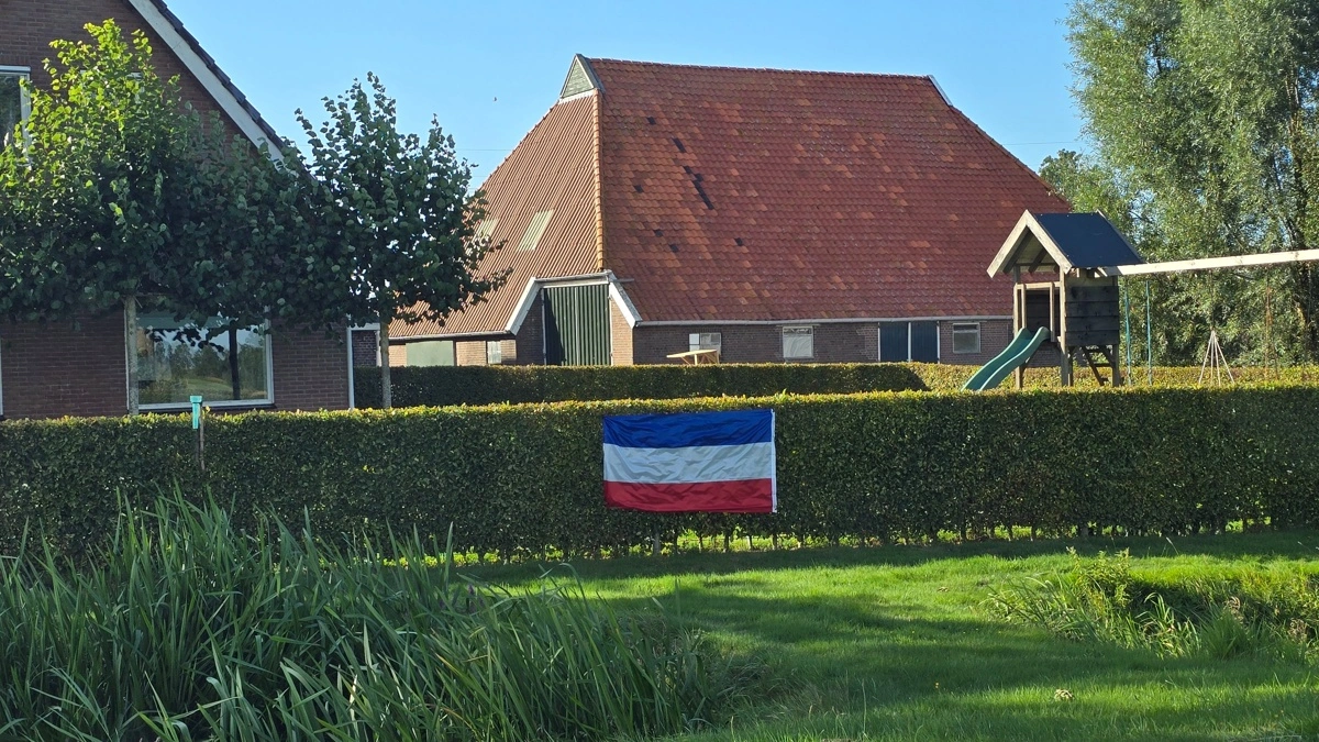 Omvendt protestflag på hækken foran kvæggård.