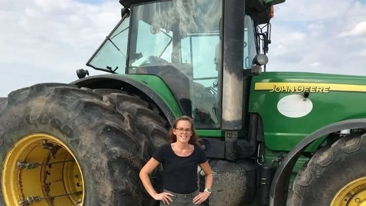 Linne Fromm-Christiansen sammen med en gammel John Deere 8520 fra 2006, RBPI´s første traktor. Den har kørt 25.000 timer, men timelønnen er så billig, at det bedre kan betale sig at renovere gearkasser og motorer i forhold til at købe nye traktorer, fortæller hun. 