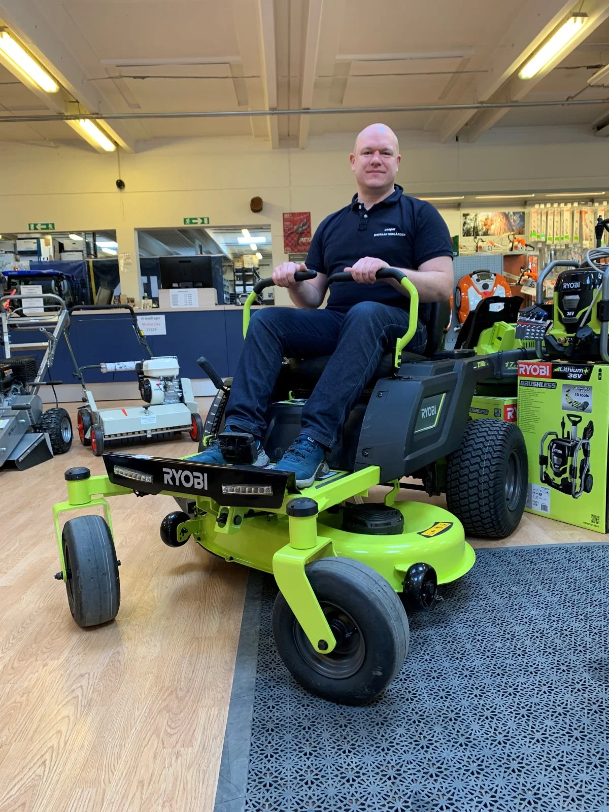 Jesper Bak, afdelingsleder hos Minitraktorgården i Køge, har taget plads i sædet på en batteridrevet plæneklipper fra Ryobi, der er en af de spændende nyheder i forretningen. Foto: Jesper Hallgren
