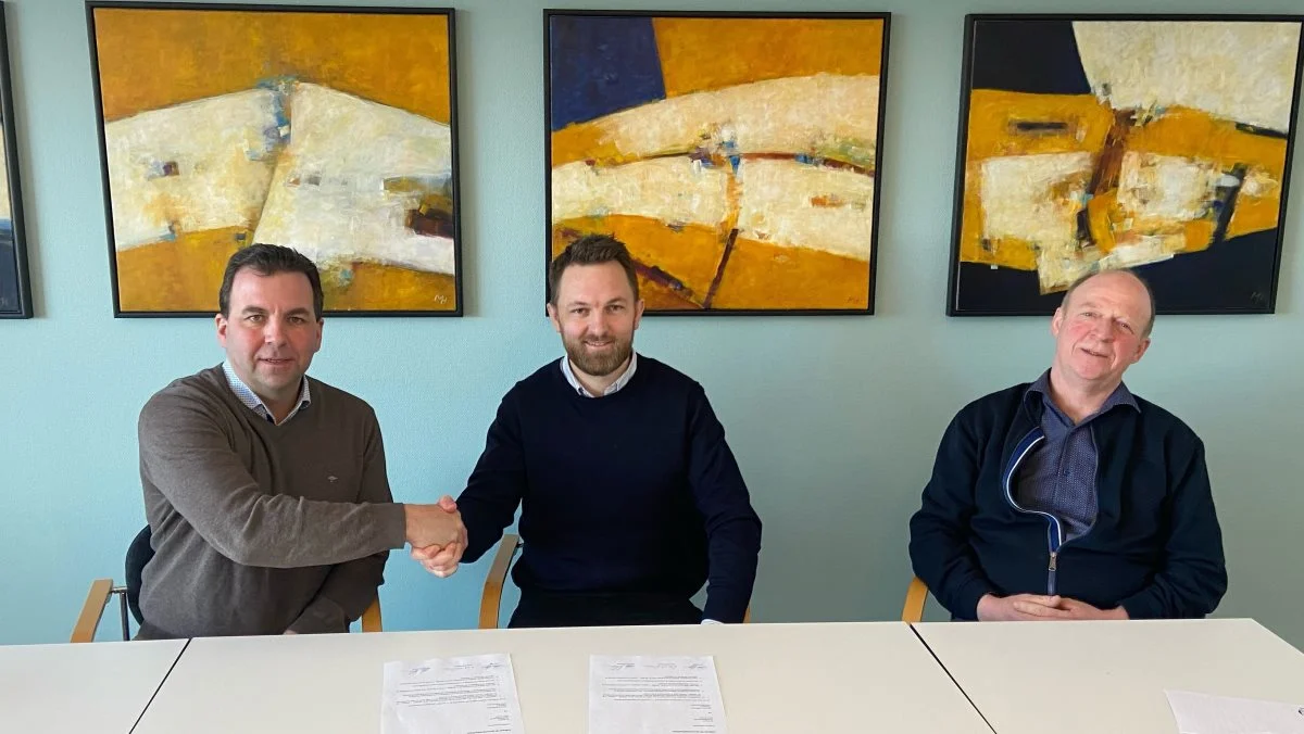 Morten Hollensen og bestyrelsesformand Peter Høj giver hånd på en underskrevet aftale. Flankeret af næstformand i Dansk Jersey Export, Niels Erik Nilsson.
