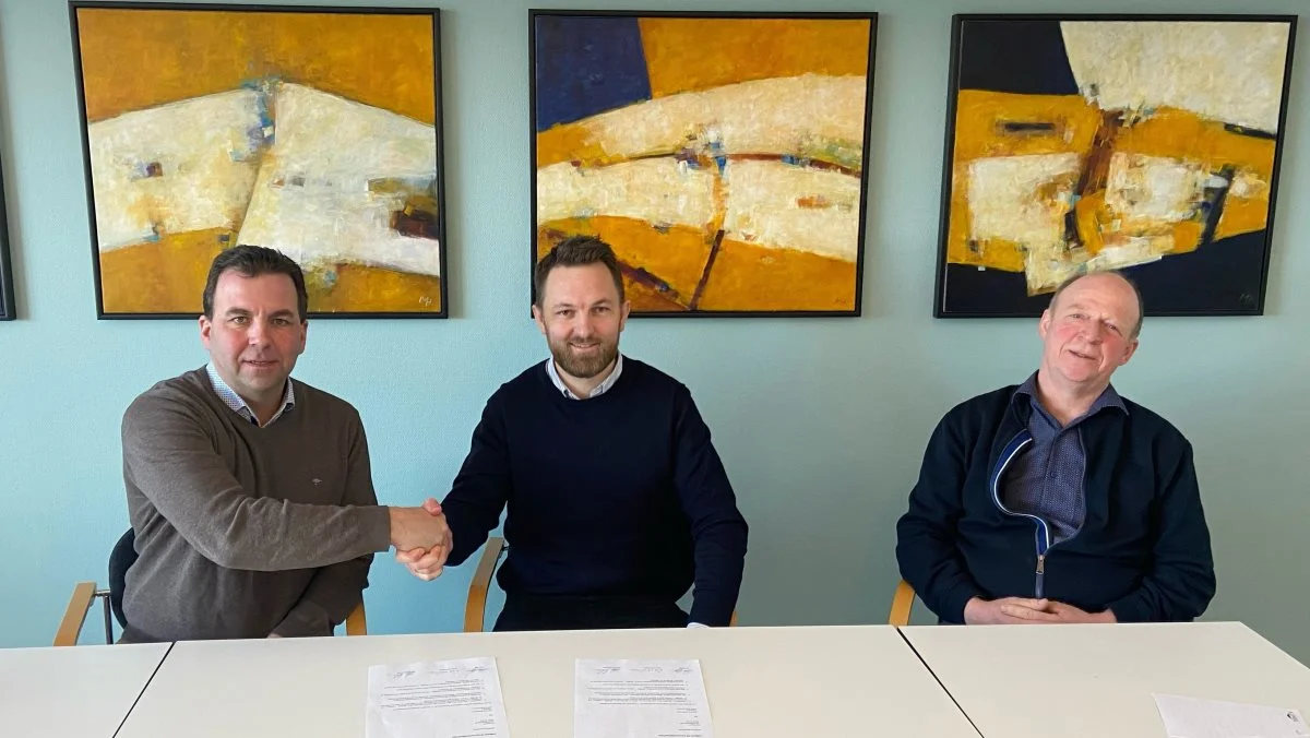 Morten Hollensen og bestyrelsesformand Peter Høj giver hånd på en underskrevet aftale. Flankeret af næstformand i Dansk Jersey Export, Niels Erik Nilsson.