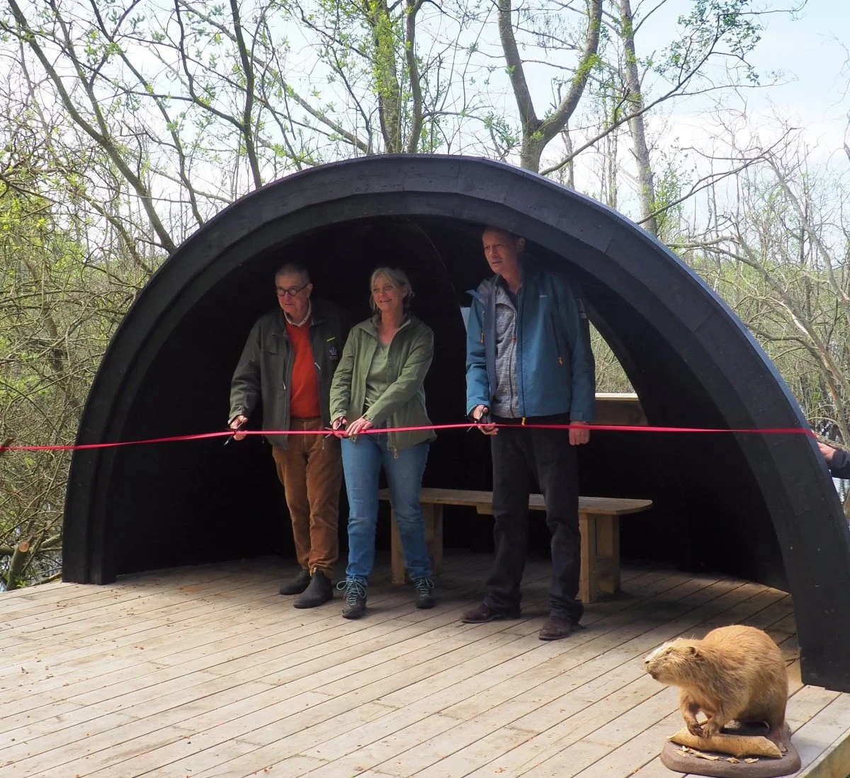 Nationalpark Kongernes Nordsjælland, Halsnæs Kommune og Naturstyrelsen står bag det nye bæverskjul, som her indvies af repræsentanter fra de tre parter. Fra venstre: Jens Bjerregaard Christensen, Naturstyrelsen, Anja Rosengren, Halsnæs Kommune, og Carl Bruun, Nationalpark Kongernes Nordsjælland. Foto: Nationalpark Kongernes Nordsjælland 