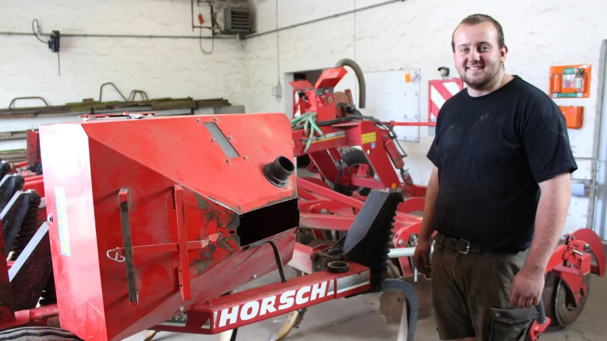 Mark Sørensen, der er elev på Hørbygaard Gods, pusler i øjeblikket med at sætte en frøsåkasse på en Horsch-harve, så den kan så efterafgrøder og harve i én arbejdsgang. Foto: Morten Ipsen
