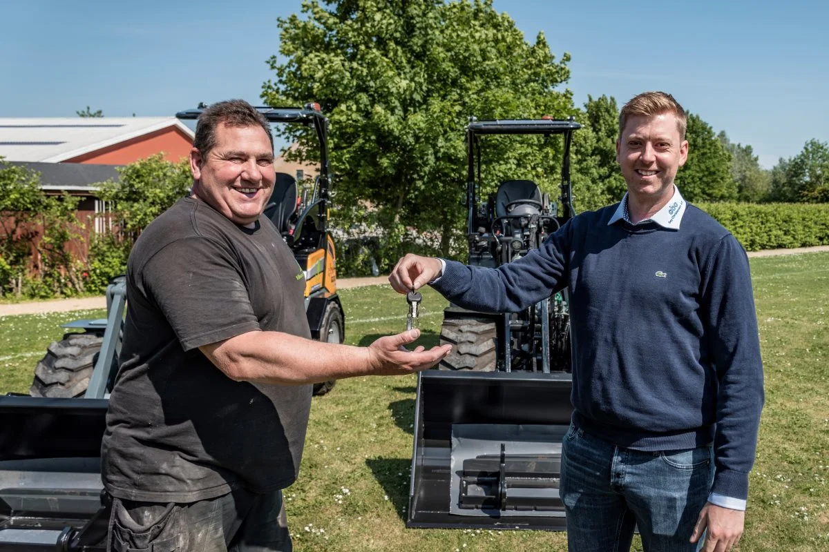 Jonas Hansen, sælger hos C. Bay Christensen (til højre), overrækker nøgler til Jens Peter Busk Pejdal, som er underviser og instruktør for anlægsgartneruddannelsen på Roskilde Tekniske Skole.