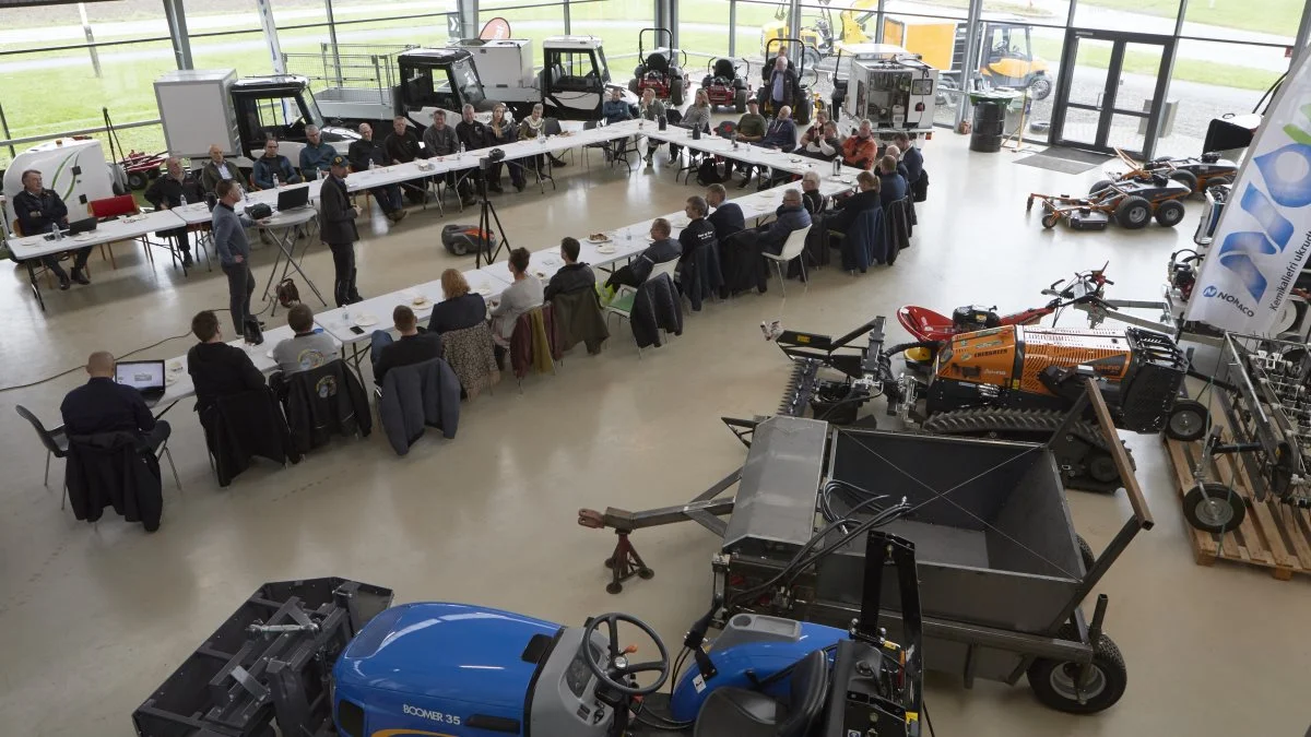Ved en temadag om biodiversitet præsenterede Glamsbjerg MaskinCenter for de omkring et halvt hundrede repræsentanter fra kommuner, boligforeninger og større offentlige virksomheder prototypen af maskinsæt, som ses nederst i forgrunden. Der er tale om en 1,20 meter skivehøster, der lægger rimlen mellem smaltraktorens hjul, og en pickup-vogn, som et par uger senere kan opsamle det tørrede materiale. Foto: Erik Hansen  