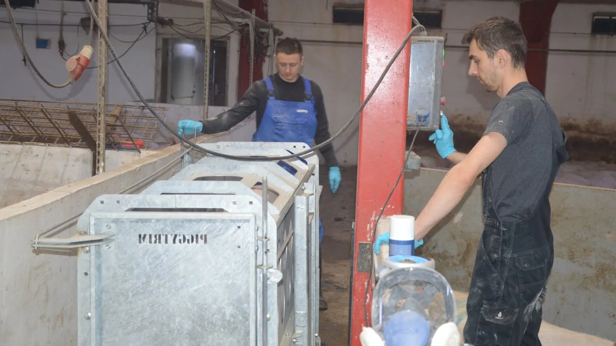 Det er let lige at drive soen hen til boksen, og er man alene om arbejdet, kan frontlågen åbnes og lukkes, selvom man er bag soen. Her hjælpes medarbejderne Artem og Alex ad med opgaven.