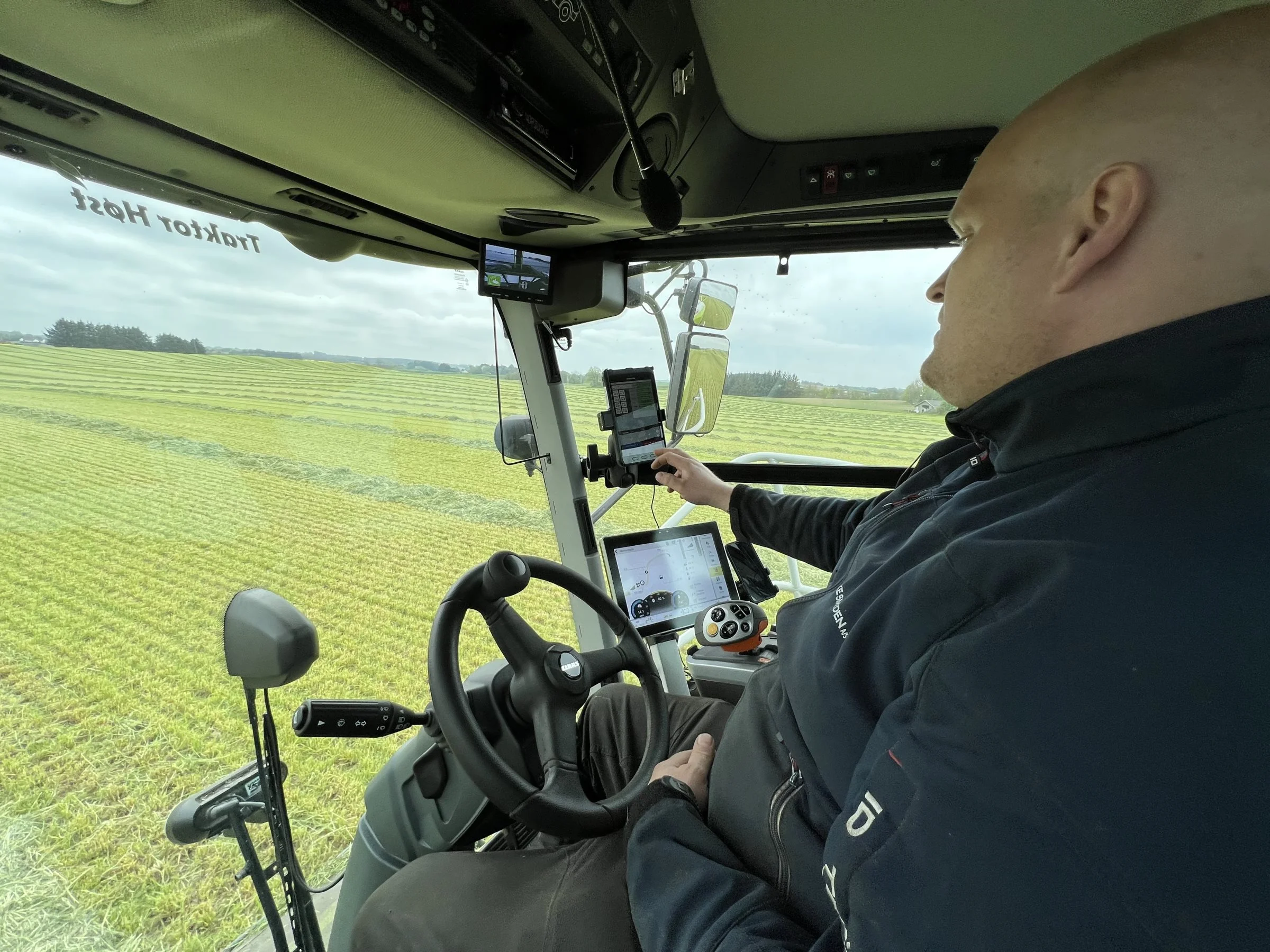 Jaguar-pilot Lasse Jakobsen viser, hvordan oplysninger om afgrødens indhold strømmer gennem tabletten, mens det bliver blæst forbi NIR-sensoren i tuden på snitteren. 