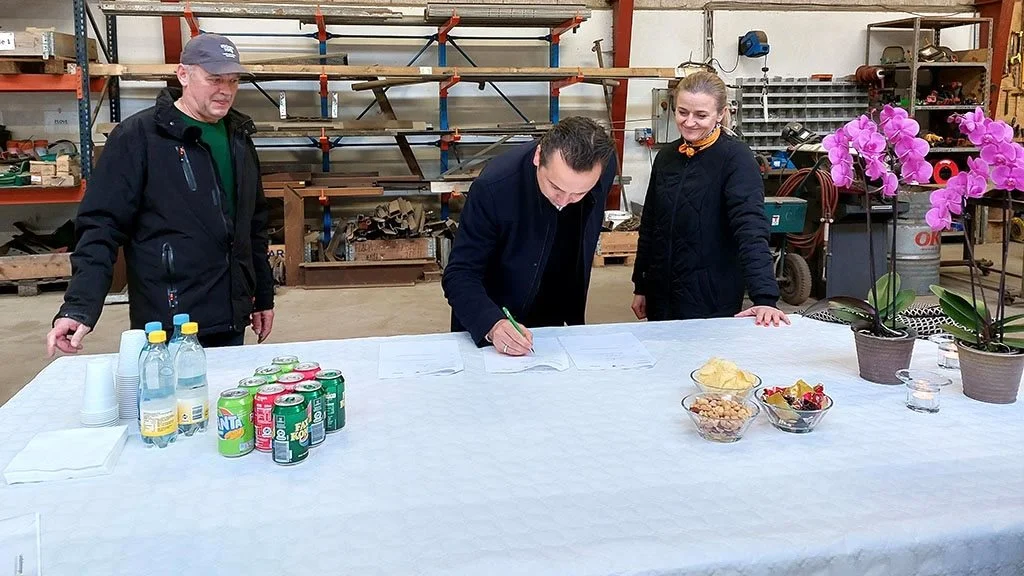 Skanderborgs borgmester Frands Fischer i gang med at skrive kontrakten med landbruget under mens Ole Larsen, (tv), og Odders borgmester, Lone Jakobi, ser til.