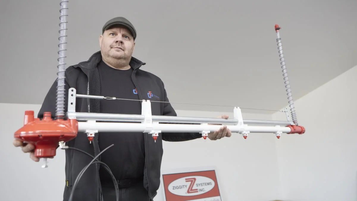 I showroomet hos Carl Fr. Petersen Maskinværksted i Løgumkloster viser direktør Henrik Brodersen et af firmaets importprodukter, Zippity vandsystemet, hvor kyllingerne aktiverer den tynde metalpind under drinkeren på vandlinjen sidevers. Derved løber vandet uden spild ned i halsen med et flow og en mængde, som bestemmes af regulatorens tryk i det pågældende aldersniveau. Foto: Erik Hansen
