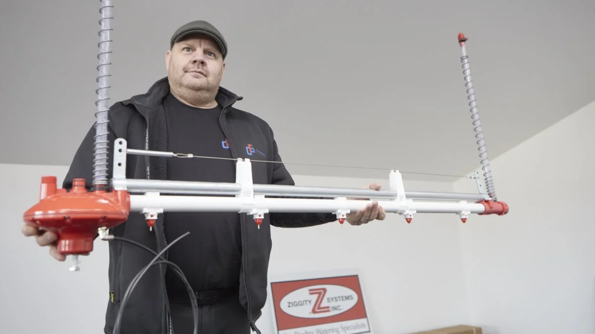 I showroomet hos Carl Fr. Petersen Maskinværksted i Løgumkloster viser direktør Henrik Brodersen et af firmaets importprodukter, Zippity vandsystemet, hvor kyllingerne aktiverer den tynde metalpind under drinkeren på vandlinjen sidevers. Derved løber vandet uden spild ned i halsen med et flow og en mængde, som bestemmes af regulatorens tryk i det pågældende aldersniveau. Foto: Erik Hansen