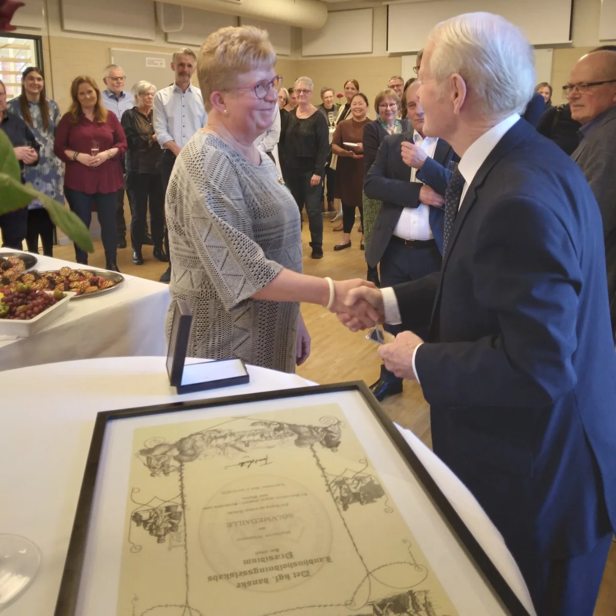 Sekretariatschef og direktionssekretær Marianne Neumann (tv) blev ved sin afskedsreception den 2. marts overrasket med Det Kongelige Danske Landhusholdningsselskabs særlige fortjenstmedalje – Sølvmedaljen »Den fortiente til ære«. Medaljen blev overrakt af Erik Klindt Andersen (th), der repræsenterede præsidiet for Det Kongelige Danske Landhusholdningsselskab. 