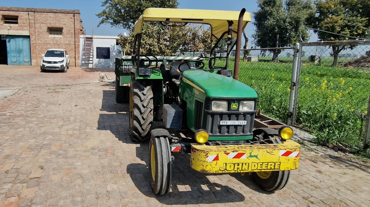 Endnu en John Deere-udgave af en traktor - typisk uden førerhus - i Indien trods stegende hede og voldsomme regnskyl.