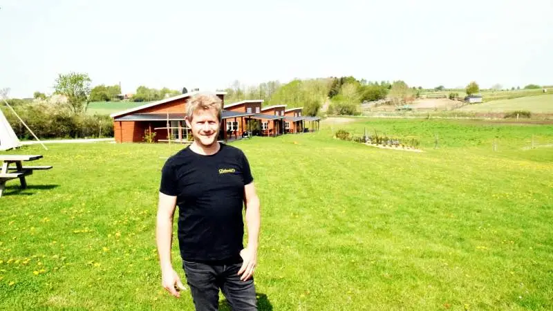 Bisonopdrætter Niels Henrik Ove, der har opdrættet bisonokser i over 25 år, ses her foran det nyeste tiltag på Ditlevsdal Bison Farm, de nybyggede præmiehuse med hver otte sovepladser.