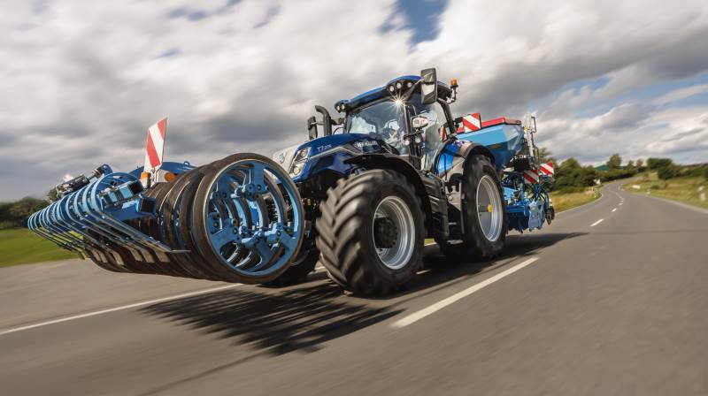 New Holland T7.225 Standard Wheelbase i Dynamic Blue-lakering under transportkørsel med liftophængt såsæt. Den nye affjedrede foraksel med dobbelte akkumulatorer og roll control-funktion forbedrer stabilitet og komfort ved høj hastighed, mens venderadiusen er reduceret med 2,4 meter fra 14,3 til 11,4 meter, der skyldes nyt forakselophæng og lavere motorhjelm. Traktoren er udstyret med 24x24 Dynamic Command-transmission. Pressefotos