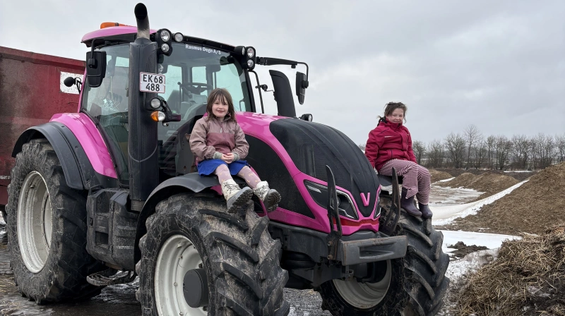 Døtrene Emilie og Ellen Marie er begejstrede for den nye traktor. - Hvis de synes, det kunne være sjovt, at far kører i en lyserød traktor, så er det da det, vi gør, siger deres far, Anders Tornslev Bach. Pressefoto
