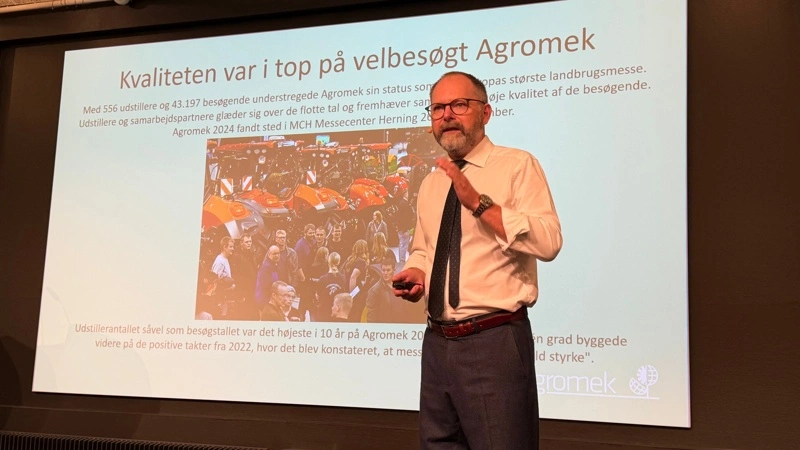 Agromek-direktør Claus Hermansen orienterede de omkring 135 deltagere ved tirsdagens kickoff om forberedelserne til Agromek 2026. Standsalget er langt fremme, og ifølge direktøren bliver alle traktormærker repræsenteret, når messen åbner i Herning den 24. november. På skærmen ses resultatet fra 2024, hvor Agromek samlede 556 udstillere og 43.197 besøgende. Foto: Per Jørgensen