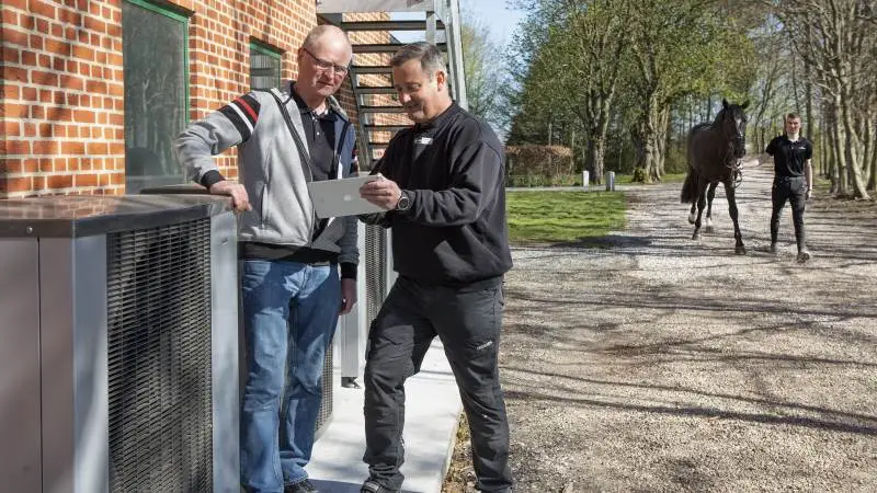 På Helgstrand Dressage sikrer fem luft-til-vand varmepumper fra Vølund Varmeteknik, at der er rigeligt med varmt brugsvand, så stedets mange heste og ryttere kan få et dagligt bad. Varmepumperne forsyner samtidig 1.200 kvadratmeter boligareal og velfærdsfaciliteter med opvarmning. Niels Erik Pedersen (tv) fra Helgstrand Dressage drøfter detalje med Henrik Højbjerg fra Højbjergs Smedie & VVS, Brønderslev.