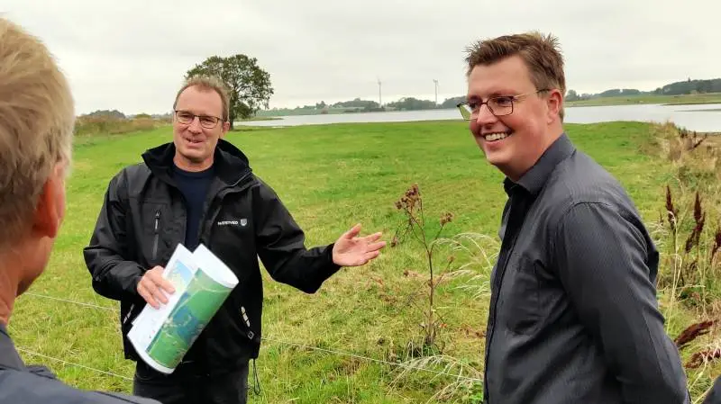 Projektleder i Næstved Kommune Søren Madsen (tv) forklarer Socialdemokratiets Kasper Roug og Lennart Damsbo-Andersen (med ryggen til) om udfordringerne ved at lave vådområder.