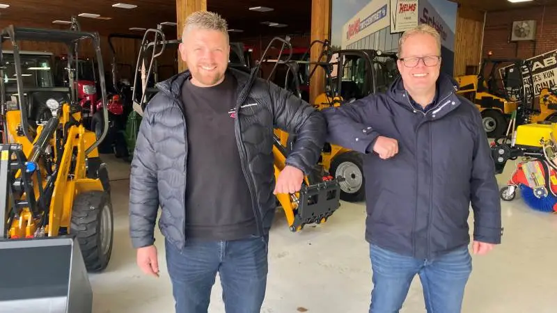 Så er det en aftale. Indehaver af Veggerslev ApS, Mads Bonde Andersen, der ses til venstre, og brand manager Allan Helms fra Helms TMT-Centret A/S havde de store smil fremme, da aftalen om Veggerslev ApS som ny Schäffer forhandler var faldet på plads. Bag dem ses en fabriksny Schäffer 2428 læssemaskine, som Veggerslev allerede har solgt. Pressefoto