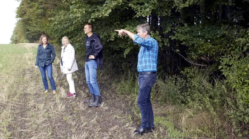 Afstanden fra staldhjørnet til statsskoven i baggrunden er trods sine 500 meter for lille. Det gør, at Lars Tolstrup ikke må udvide, da han ikke kan overholde ammoniakkravene, selv om udledningen faktisk bliver 20 procent lavere, end den er i dag. Folketingsmedlem Lise Bech fra Dansk Folkeparti (nummer to fra venstre) samt Ida M. L. D. Storm og Anders Panum Jensen fra Landbrug & Fødevarer lytter med. Fotos: Tenna Bang