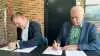 Borgmester i Guldborgsund Kommune, Simon Hansen (tv.), og næstformand i den rådgivende landbrugsorganisation VKST, John Nielsen (th.) skrev torsdag under på en partnerskabsaftale, der forpligter parterne til et tæt samarbejde om reduktion af CO2-udledningen. Foto: Guldborgsund Kommune